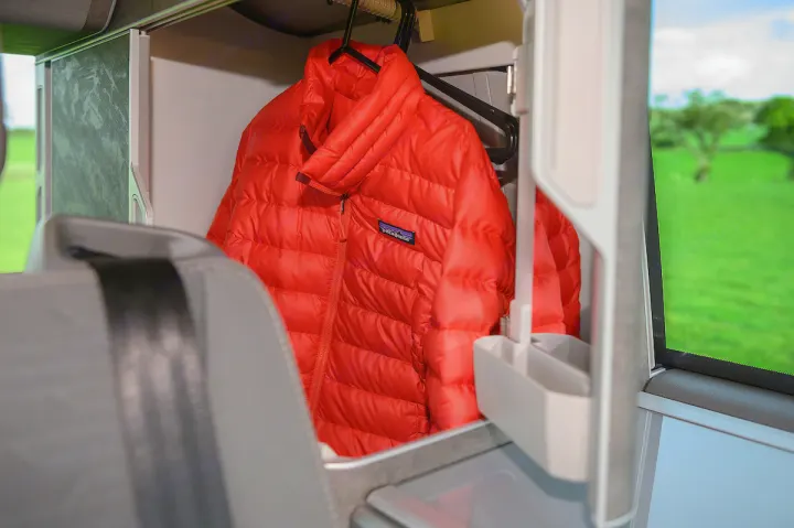 Red Patagonia puffer jacket hangs in an RV rental. Efficient interior storage for organized, comfortable travel adventures.. Volkswagen California Ocean 2024