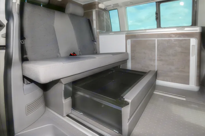 Spacious RV rental interior showing pull-out under-seat storage drawer and modular bench seating. Perfect for camper van trips.. Volkswagen California Ocean 2024