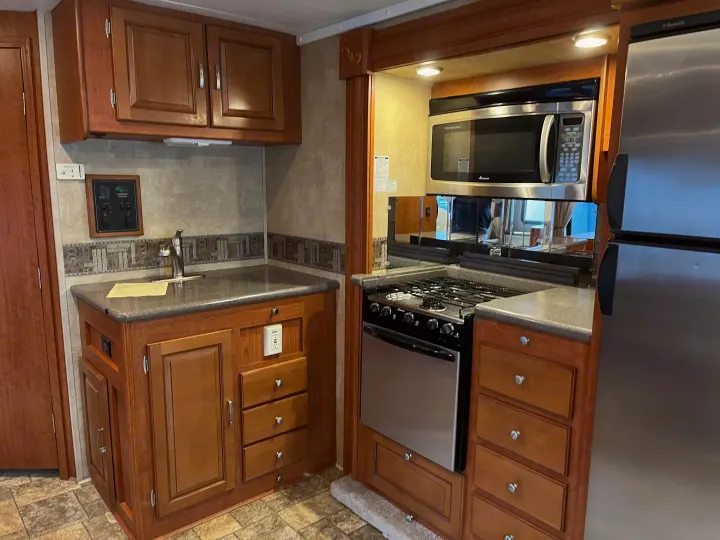 Functional RV rental kitchen: wood cabinets, sink, microwave, stove, refrigerator, plus a command center.. Forest River Georgetown M373DS 2011