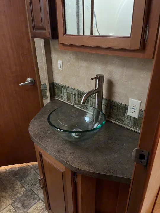 RV rental bathroom: A clear glass bowl sink, sleek faucet, and dark wood vanity counter.. Forest River Georgetown M373DS 2011