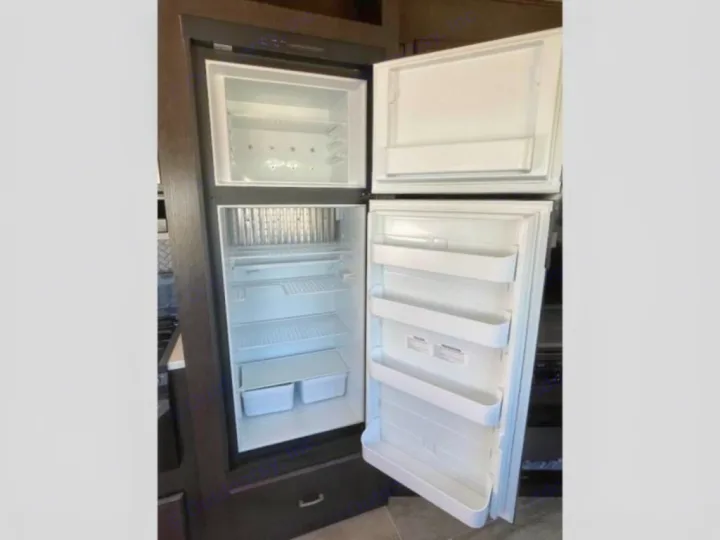 An open, empty two-door refrigerator/freezer in an RV rental, ready for your adventure.. Heartland RVs Pioneer 2020
