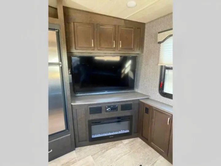 Enjoy this modern RV rental's cozy living area with TV, electric fireplace, cabinets, and fridge. Your road trip comfort awaits!. Heartland RVs Pioneer 2020