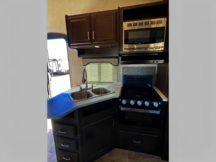 RV rental kitchen interior: dark cabinets, double sink, microwave, and stove with oven. Ready for cooking!. Heartland RVs Pioneer 2020