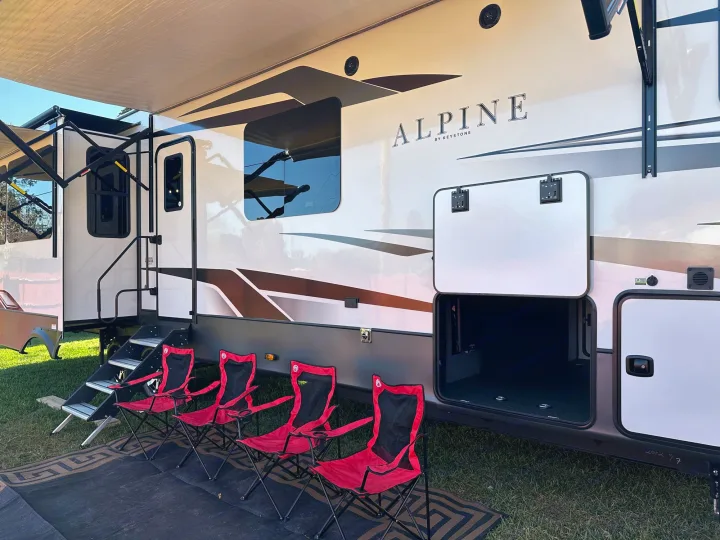 Spacious RV rental setup with extended awning, camping chairs, and ample storage for your travels.. Keystone RV Alpine 2022