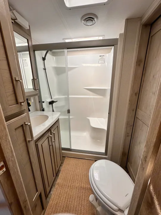 Compact RV rental bathroom featuring a shower, vanity with sink, and toilet. Ideal for travel comfort.. Keystone RV Alpine 2022