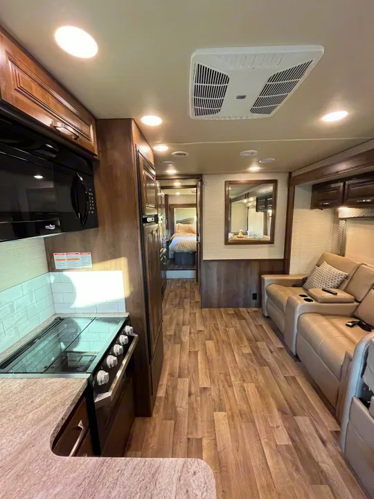Inside a modern RV rental featuring a full kitchen, living space with recliners, and a rear bedroom.. Jayco Greyhawk 2020