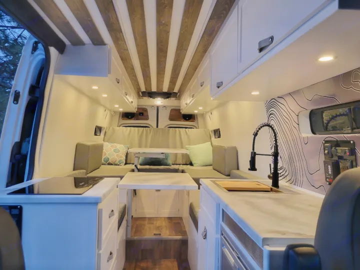 Modern RV rental interior with full kitchen, comfortable living area, and stylish wood-slat ceiling.. Mercedes-Benz Sprinter 2022