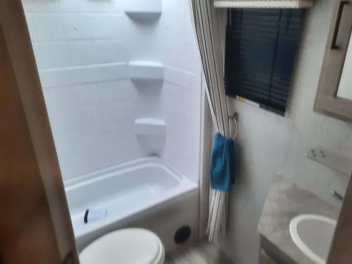 Clean RV rental bathroom with compact tub/shower, toilet, and sink area. Ready for your road trip comfort.. Forest River Rockwood Mini Lite 2021