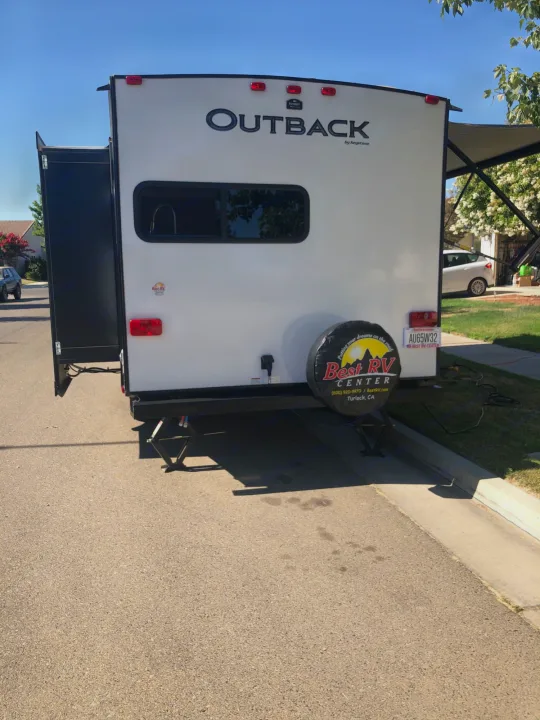 Rear view of an Outback travel trailer RV rental, with slide-out and awning extended, parked for camping.. Keystone RV Outback Ultra-Lite 2019