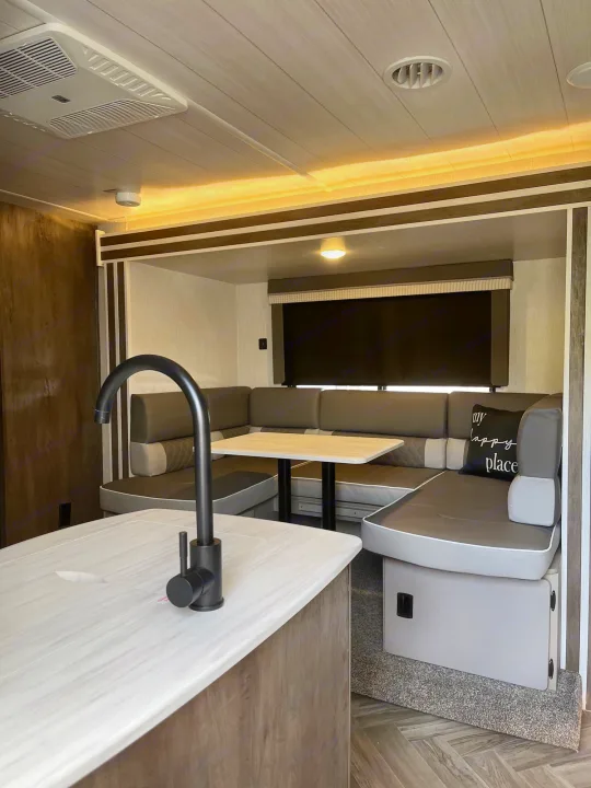 Modern RV rental interior: kitchen island, U-shaped dining booth, and cozy living space for a comfortable trip.. Forest River Wildwood X-Lite 2022