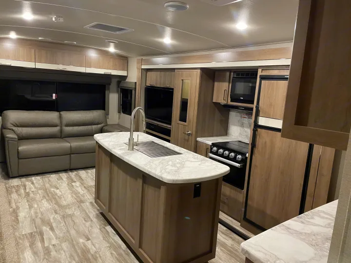 Step inside this clean RV rental! Modern interior features a full kitchen with island, appliances, & living area with a comfy sofa.. Grand Design Imagine 2022