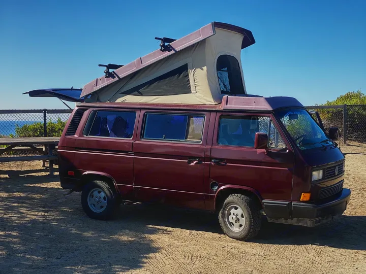 Burgundy VW pop-top camper van, perfect for an RV rental adventure by the coast.. Volkswagen Westfalia 1990