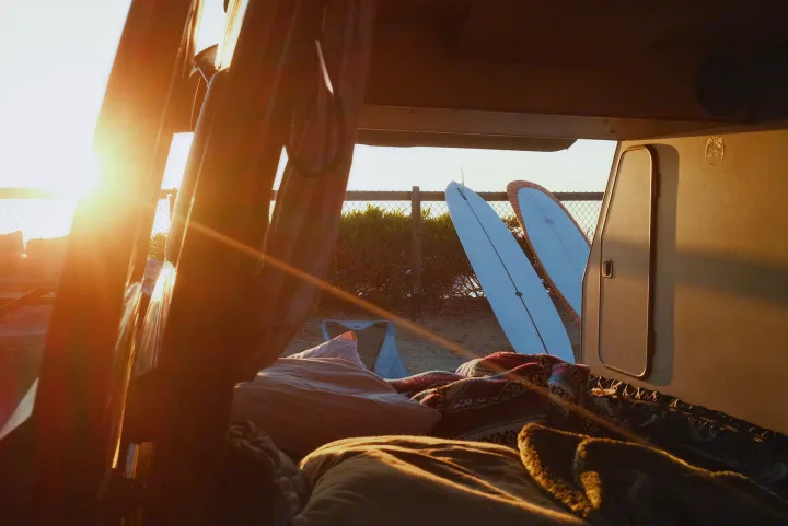 Cozy RV rental view at sunset, with surfboards ready for the waves. Perfect beach camping from inside a van.. Volkswagen Westfalia 1990