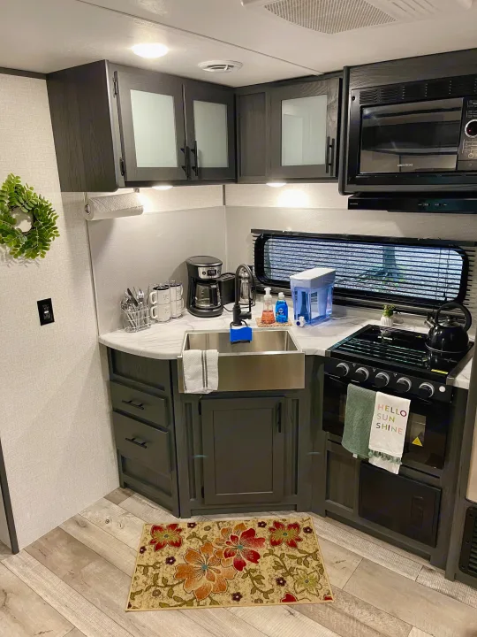 RV rental kitchen with modern amenities: sink, stove, microwave, and coffee maker. Clean and functional for travel.. Dutchmen Aspen Trail 2022
