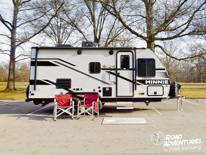 An RV rental, a Micro Minnie travel trailer, parked on asphalt with chairs set up for outdoor relaxation.. Winnebago Micro Minnie 2100BH 2023