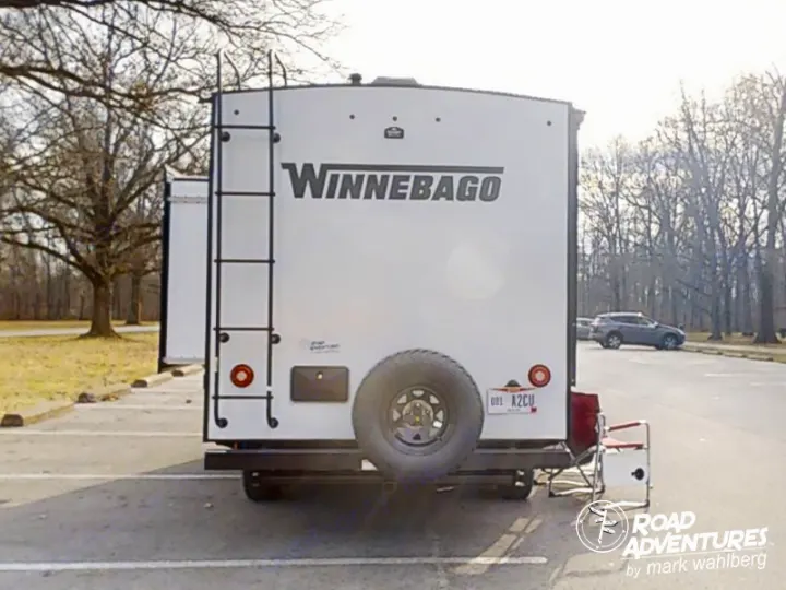 This Winnebago rv rental is ready for adventure! Rear view shows a ladder, spare tire, and chair in a park lot.. Winnebago Micro Minnie 2100BH 2023