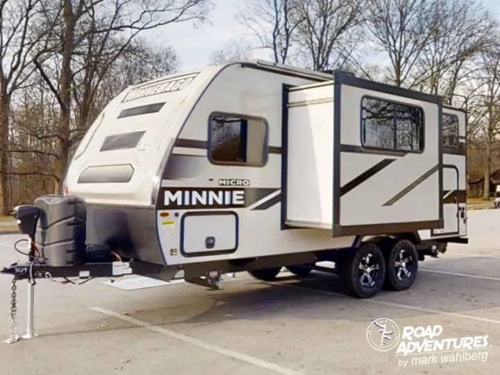 White Winnebago Minnie Micro travel trailer with extended slide-out, parked on asphalt, ready for an rv rental adventure.. Winnebago Micro Minnie 2100BH 2023