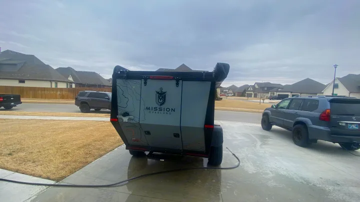 Mission Overland trailer, a rugged option for RV rental, on a wet driveway. Suburban homes and vehicles visible.. Mission Overland Mission Overland Trailer 2020