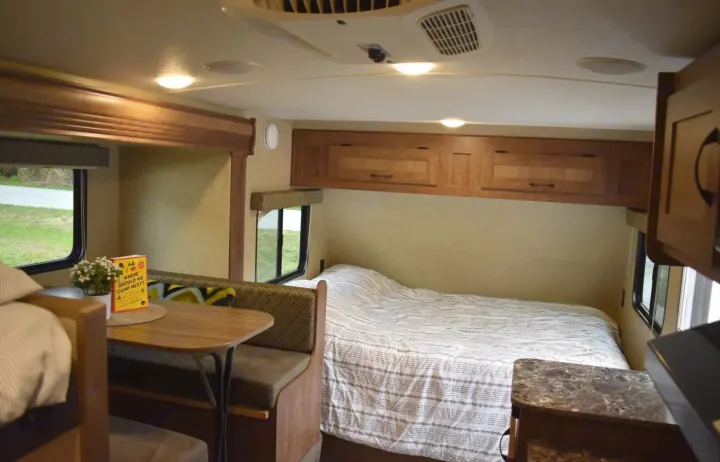 Cozy RV rental interior showcasing a comfortable bed, functional dinette, and overhead storage—ideal for your next camping trip.. Starcraft Autumn Ridge Mini 2017