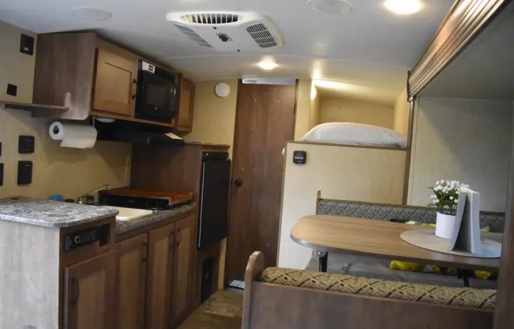 Inside this **rv rental**: a cozy kitchen area, dining table with patterned benches, and a comfortable bunk bed. Ideal for road trips.. Starcraft Autumn Ridge Mini 2017