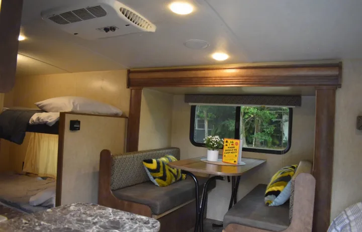 Spacious RV rental interior featuring bunk beds, a dinette with bench seating, and an outdoor view, perfect for camping.. Starcraft Autumn Ridge Mini 2017