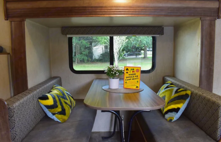 Cozy RV rental dinette with a table, bench seats, and vibrant pillows. Large window view, ready for your next camping adventure.. Starcraft Autumn Ridge Mini 2017
