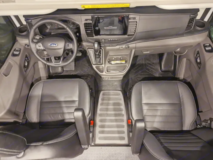 Overhead view of a modern Ford van interior, ideal for rv rental. Features dashboard, steering wheel, shifter, and two black leather seats.. Grit Overland GO A/T 2022