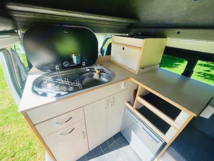 Experience mobile living: This rv rental features a compact campervan kitchen with stove, sink, fridge, and storage.. Toyota Hiace 2014