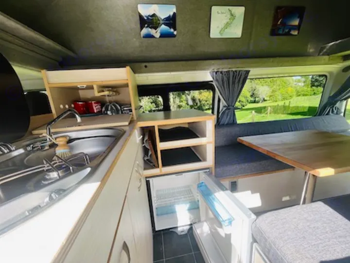 Inside this RV rental: compact kitchen with sink/stove, dining area, & fridge. Perfect for road trips & adventure.. Toyota Hiace 2014