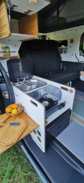 RV rental van interior features a compact kitchenette (sink, stove, fridge), pull-out table, and comfortable rear seating.. Renault Trafic 2023