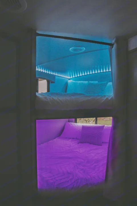 Cozy RV rental bunk beds feature vibrant blue and purple LED lighting, offering a comfortable, colorful sleeping area.. Heartland RVs Sundance Ultra Lite 2021