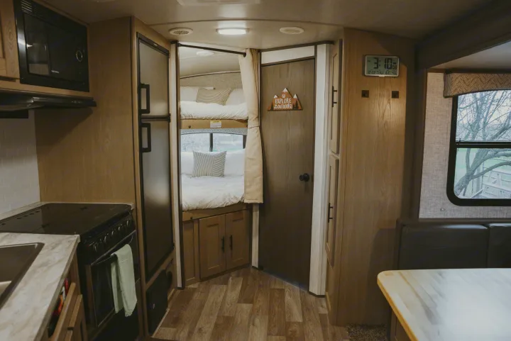 Inside a modern RV rental: a well-equipped kitchen, comfy bunk beds, and a dining area. Perfect for family adventures.. Heartland RVs Sundance Ultra Lite 2021