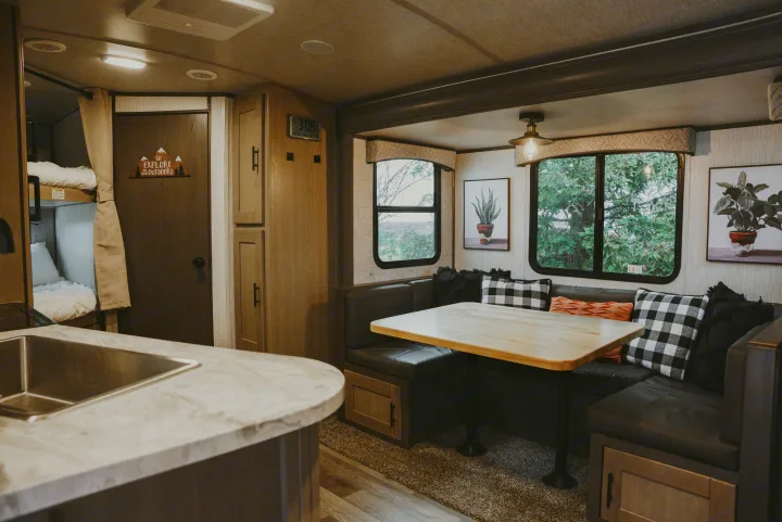 Cozy RV rental interior: a comfortable dinette, kitchen counter, and bunk beds, with scenic window views.. Heartland RVs Sundance Ultra Lite 2021