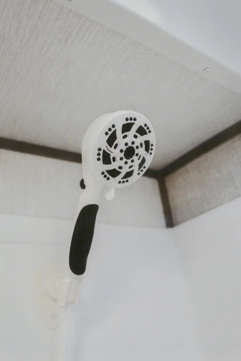 A white Oxygenics handheld shower head, often found in a modern RV rental bathroom, shown against a light interior.. Heartland RVs Sundance Ultra Lite 2021