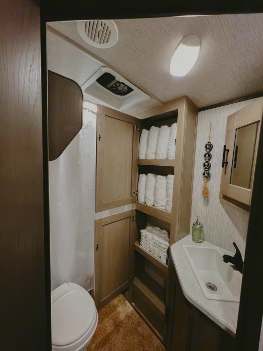Compact RV rental bathroom with shower, toilet, sink, and ample towel storage. Bright and functional interior.. Heartland RVs Sundance Ultra Lite 2021