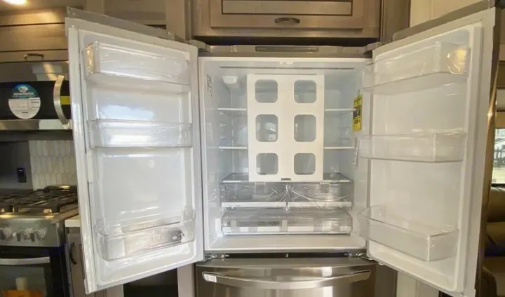 Spacious, empty refrigerator with French doors in an RV rental kitchen. Clean interior, bottom freezer, ready for your trip.. Forest River Other 2022