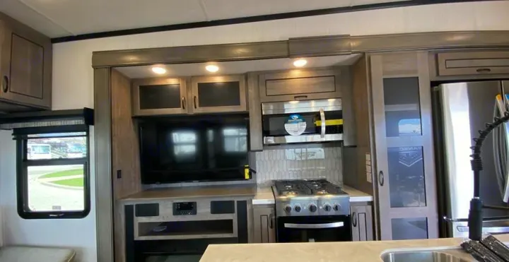 Modern RV rental kitchen and living area with TV, microwave, stove, refrigerator, and ample storage.. Forest River Other 2022