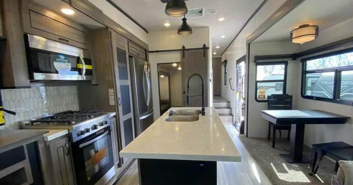 Spacious, modern RV rental interior featuring a full kitchen with an island, stove, microwave, and dining area.. Forest River Other 2022