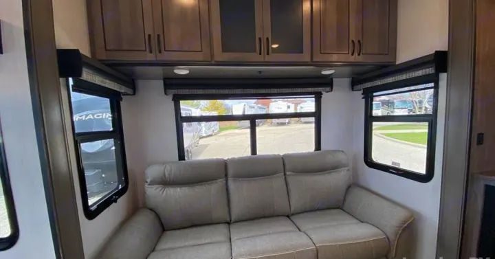 Inviting RV rental interior: living area with a plush sofa, wide windows, and practical overhead cabinets.. Forest River Other 2022