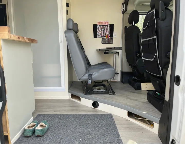 Cozy RV rental camper van interior with grey seating, wall-mounted table, unicorn art, and slippers.. Ram Promaster 2022