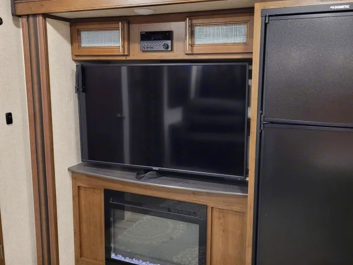 Inside an rv rental, featuring an entertainment center with TV, electric fireplace, and Dometic refrigerator.. Keystone RV Cougar 2020