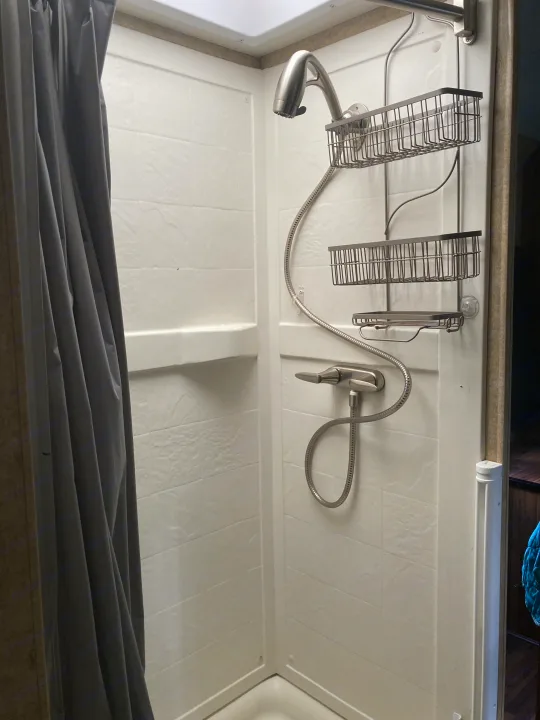 Clean, modern shower in an RV rental. Features a flexible showerhead, hose, and two storage caddies for toiletries.. Thor Majestic 2016