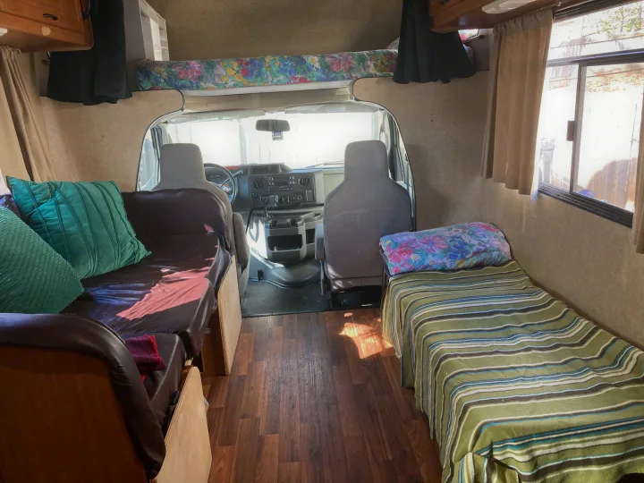 RV rental interior: A bright, cozy camper living space with driver's cabin, bed, and seating, featuring wood floors.. Thor Majestic 2016