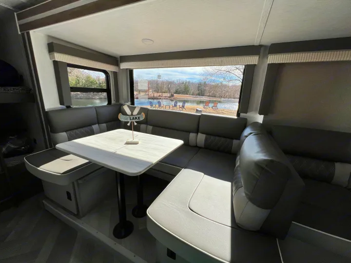 Inside a spacious RV rental, a comfy U-shaped dinette offers serene lake views through large windows.. Forest River Wildwood X-Lite 2022