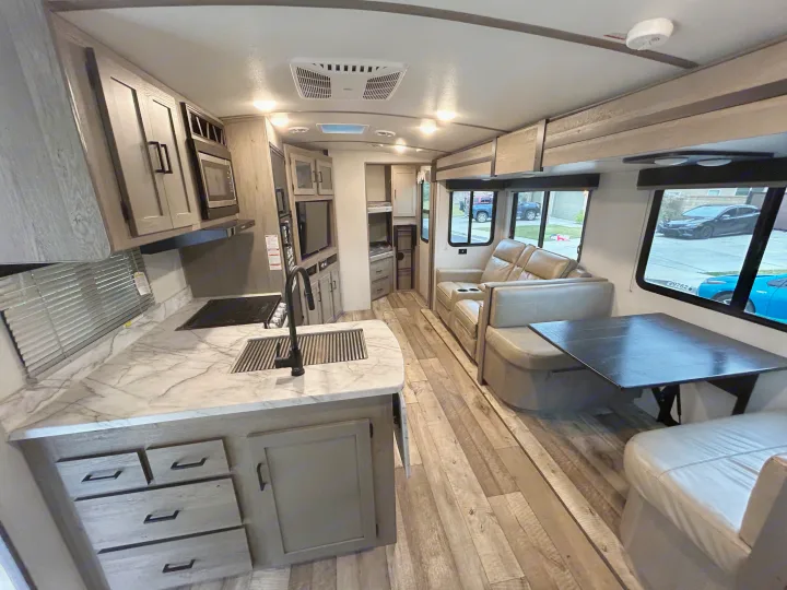 Inside a stylish RV rental: modern kitchen, cozy recliners, and dining table. Hardwood floors throughout.. Keystone RV Outback Ultra-Lite 2021