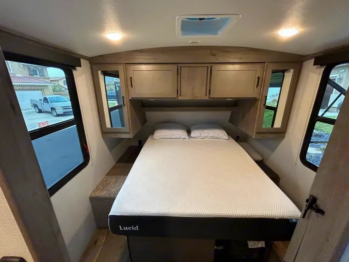 RV rental bedroom: A comfortable bed, overhead cabinets, and bright windows for your travels.. Keystone RV Outback Ultra-Lite 2021