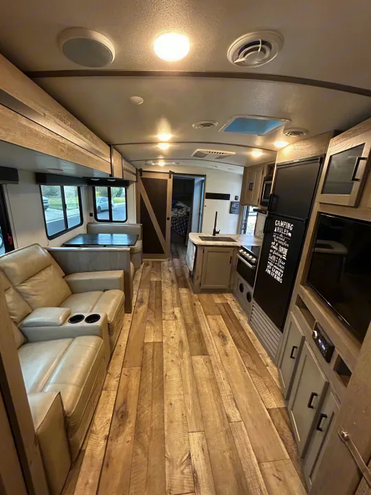 Modern RV rental interior with comfortable recliners, dining booth, and fully equipped kitchen. Ideal for memorable trips.. Keystone RV Outback Ultra-Lite 2021