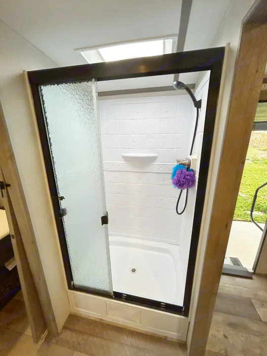 Modern and clean shower in an RV, ready for your next rv rental. Features include a skylight and frosted glass door for privacy.. Keystone RV Outback Ultra-Lite 2021