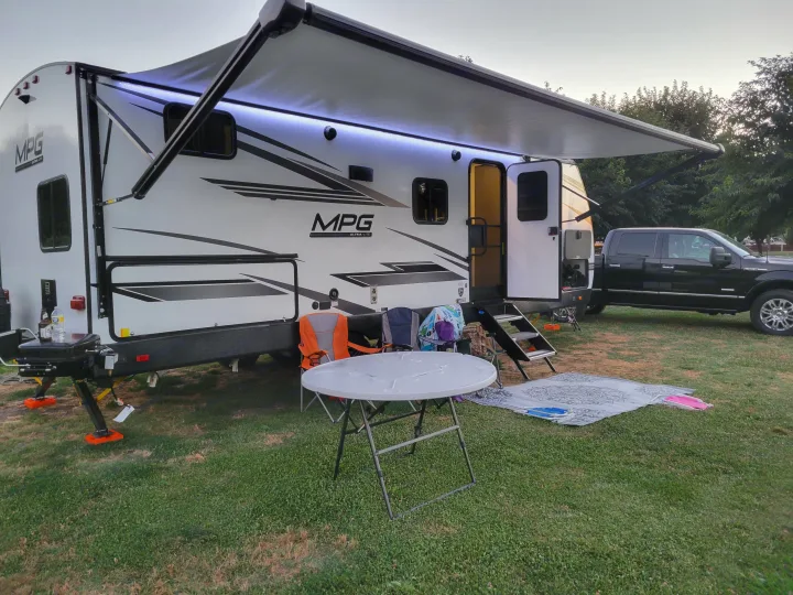 Enjoying a peaceful RV rental getaway. This travel trailer is set up with an illuminated awning, outdoor area, and truck.. Cruiser RV MPG Ultra Lite 2022