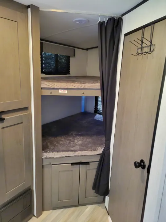 RV rental interior features bunk beds (275 lbs max), privacy curtain, and built-in storage cabinets.. Cruiser RV MPG Ultra Lite 2022
